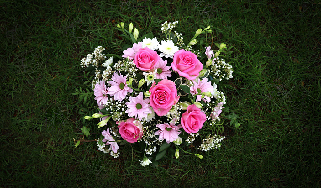 Beautiful bouquet of pink roses and carnations sitting on grass, specially made for Mothering Sunday